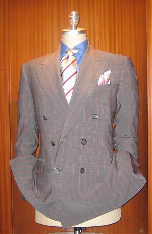 A beautiful and lightweight suit with a red chal stripe, outlined by a white pinstripe. A darker blue shirt for the lighter shade of the suit complements the salute to spring. The repp tie once again used to blend suit and shirt together.